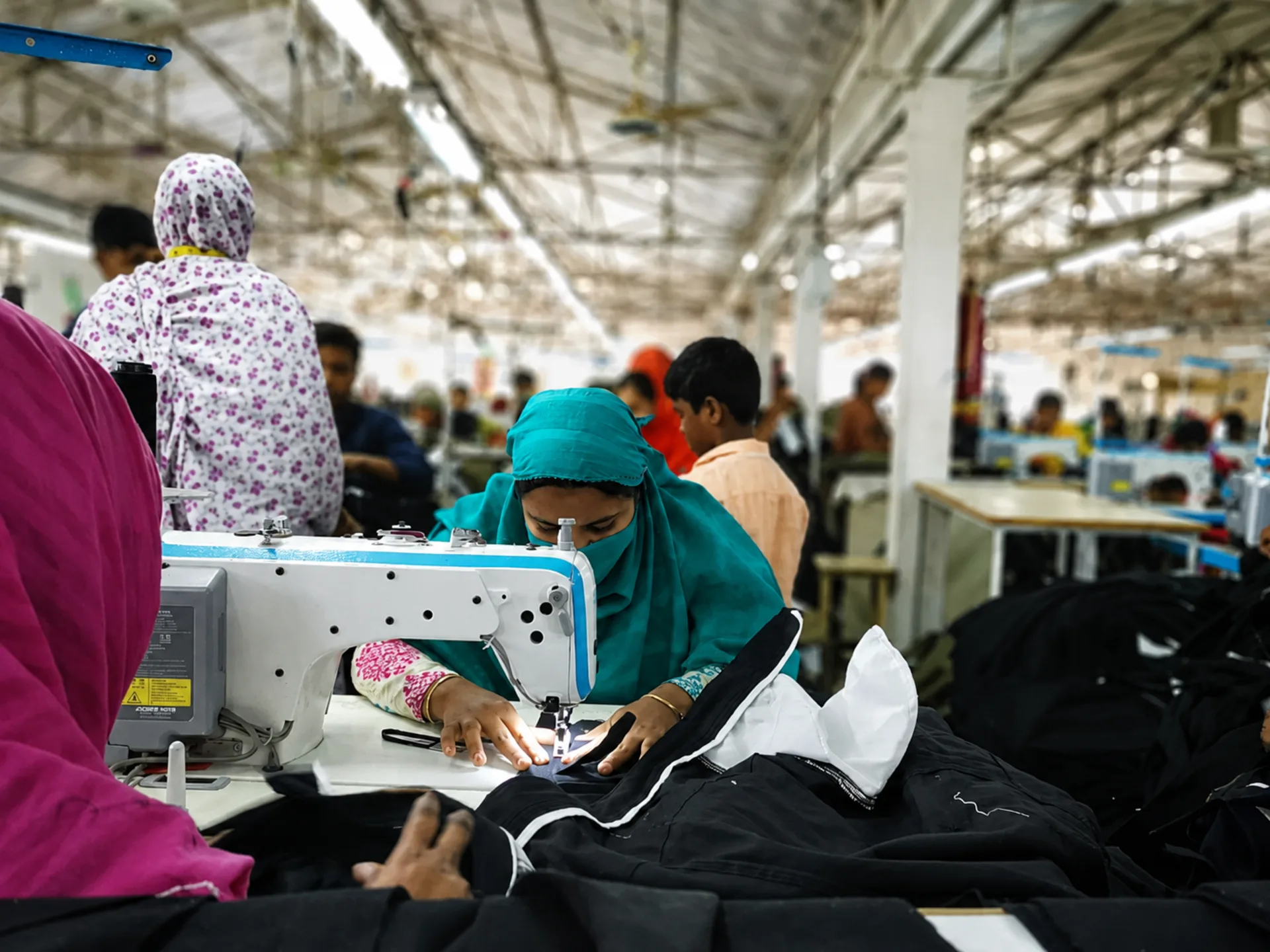 Skilled machinists sewing premium garments on the production floor at Essential Group's Dhaka factory
